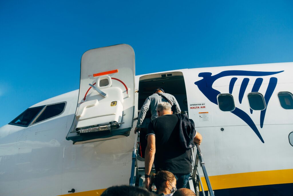 Passagiere steigen über die Gangway in ein Ryanair Flugzeug ein, ideal zur Veranschaulichung der strengen Handgepäck Kontrollen beim Boarding.